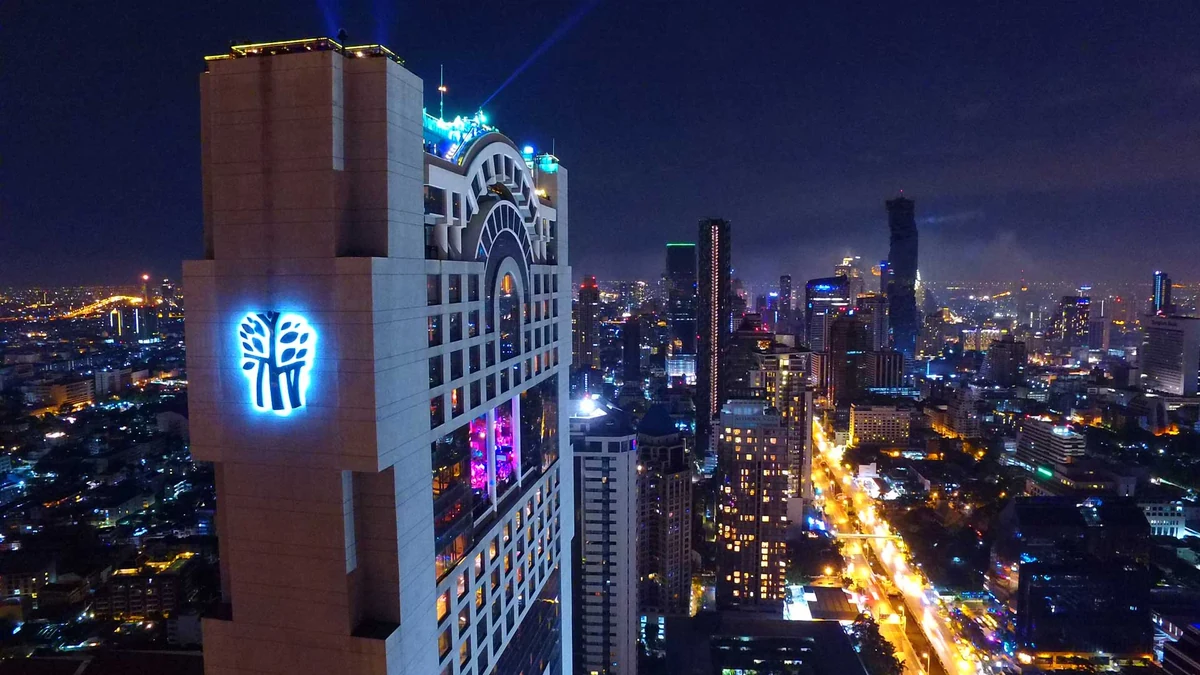 夜色中高於曼谷天際線的 Banyan Tree Bangkok，樹形標誌亮起，上部外觀呈拱形