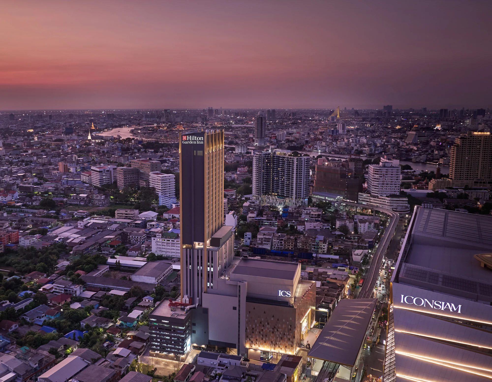 Tour de Hilton Garden Inn Bangkok Riverside avec son enseigne au-dessus d’ICS, près d’ICONSIAM et du Chao Phraya au crépuscule