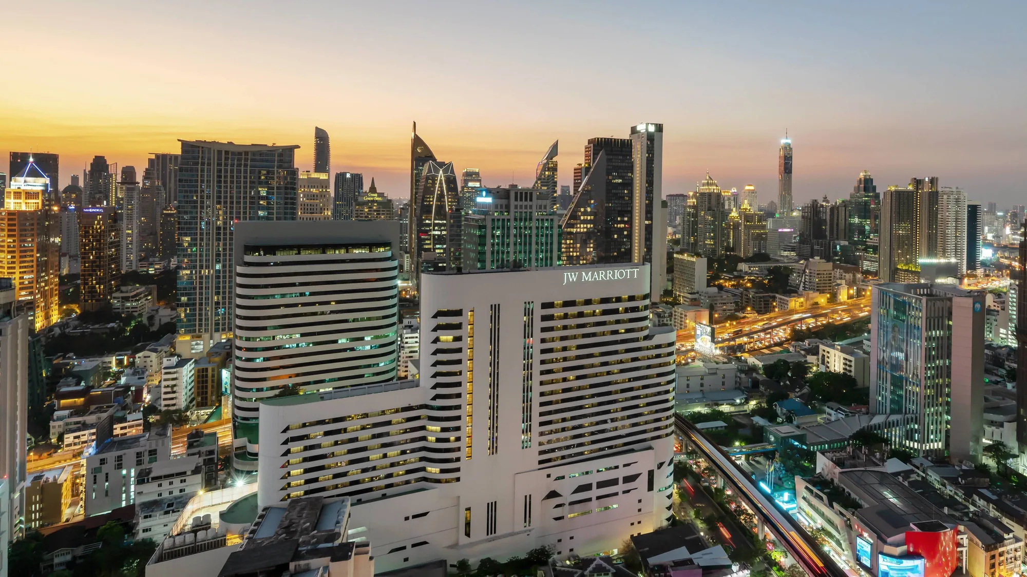 Tours du JW Marriott Hotel Bangkok et nom de l’hôtel éclairé au-dessus de Sukhumvit Road au crépuscule