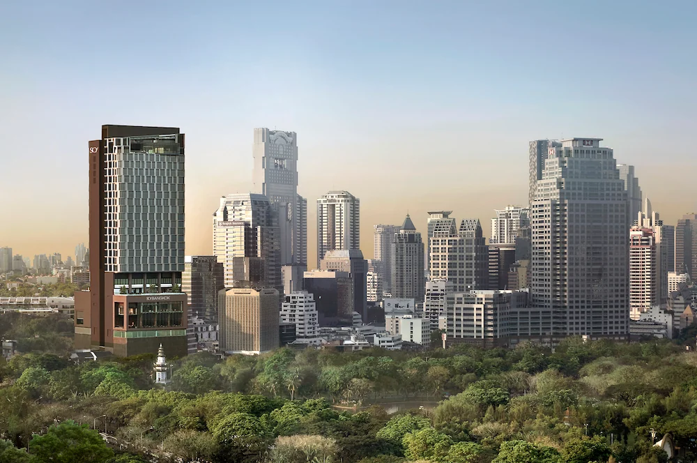 Der dunkle Turm des SO/ Bangkok neben den Bäumen des Lumphini-Parks.