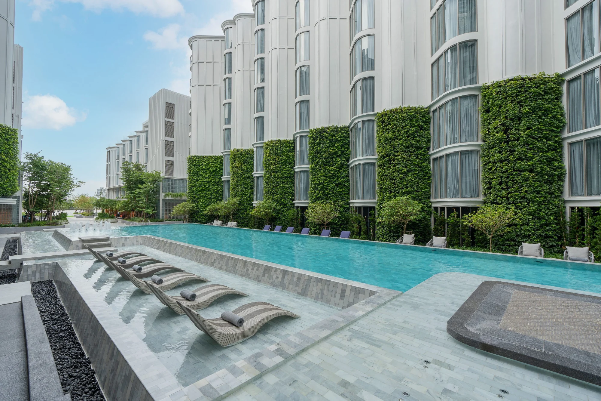 The Salil Hotel Riverside Bangkok’s curved white facade and vertical gardens beside its courtyard pool