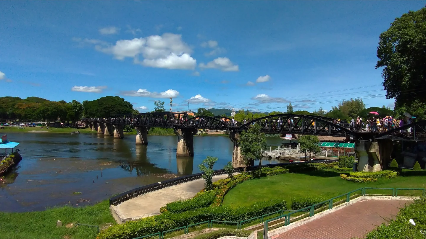 The River Kwai Bridge crossing the river in Kanchanaburi beneath a blue sky
